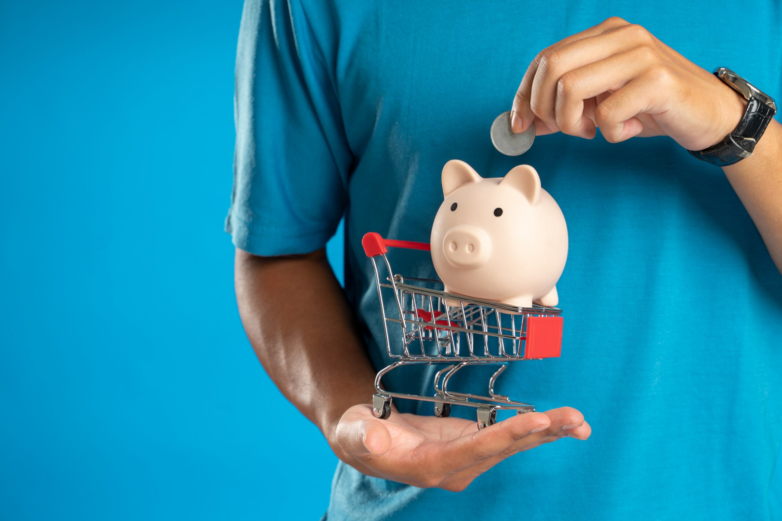 man holding miniature piggy bank and shopping trolley. Source: https://ukrn.org.uk/app/uploads/2022/10/pexels-dany-kurniawan-12357532.jpg