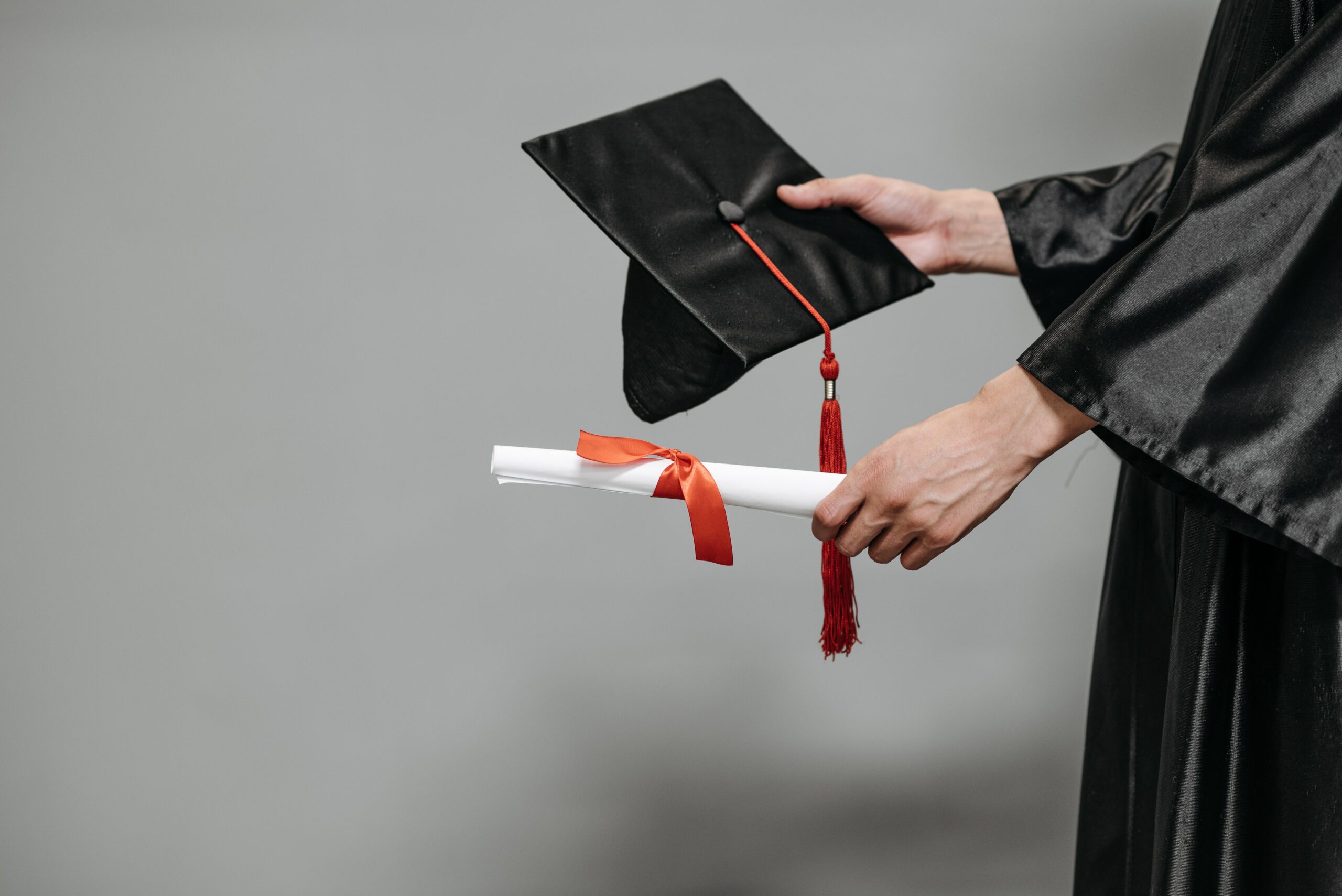 person in black graduation robe with mortarboard and certificate